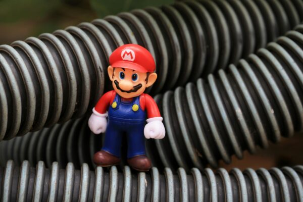 Close-up of a Super Mario toy figure standing among coiled plastic tubes.