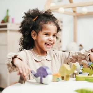 A joyful young girl playing with wooden toys, showcasing pure childhood happiness.