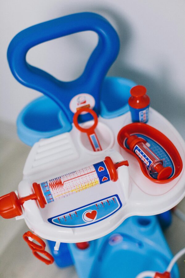 Plastic toy medical kit featuring a syringe and other tools for pretend play by children.