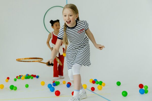 Two girls having fun playing indoors with rackets and colorful balls, full of joy.